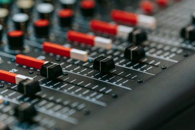 Vertical shot of a professional audio mixer with red potentiometers and switches.